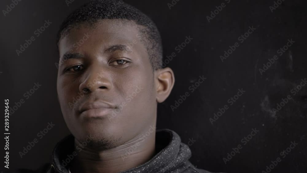 Confident handsome young African American male in the dark, looking at camera Confident handsome young African American male in the dark, looking at camera