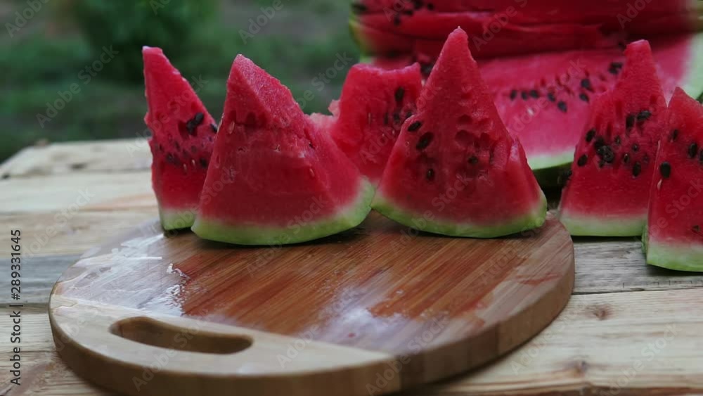 People takes cut pieces of juicy ripe watermelon on wooden table, top view. People takes cut pieces of juicy ripe watermelon on wooden table, top view.