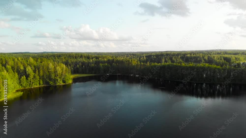 Aerial, drone shot over calm waters, on lake Liesjarvi, towards green forest, on a sunny, summer evening, in a finnish national park, in Kanta-hame, Finland Aerial, drone shot over calm waters, on lake Liesjarvi, towards green forest, on a sunny, summer evening, in a finnish national park, in Kanta-hame, Finland