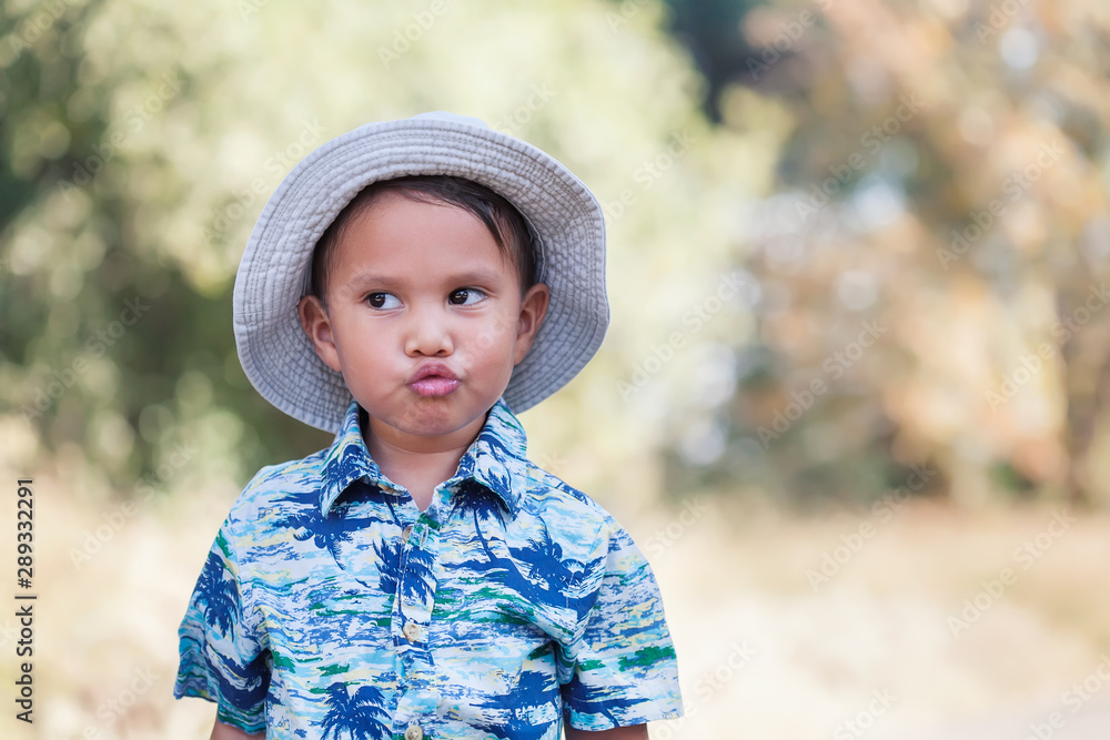 Cute young boy wearing a tropical print shirt and hat who is blowing kisses while looking away to the distance. Cute young boy wearing a tropical print shirt and hat who is blowing kisses while looking away to the distance.