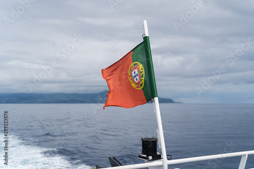 Portuguese flag on a ferryboat between Azores Islands against cloudy sky, Portugal