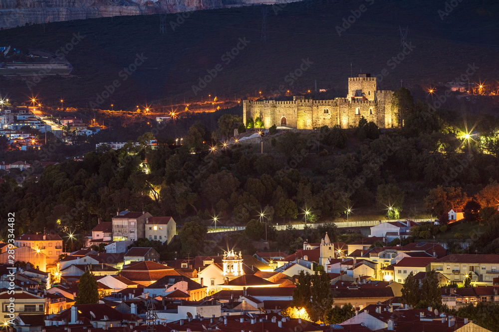 Pombal castle in Portugal, seen from the viewpoint at dusk, with part of the city of Pombal at the base of the hill.