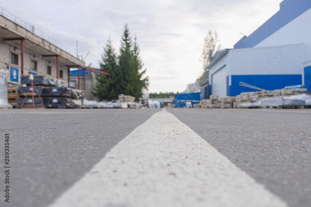 Road marking line on asphalt in the territory of an industrial facility in the summer. Ground level view Road marking line on asphalt in the territory of an industrial facility in the summer. Ground level view
