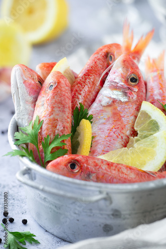 Quadro em tela Fresh striped red mullet in a tin basket with slices of lemon and parsley leaves