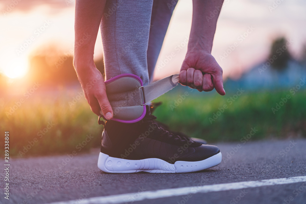 Athletic man puts on sports weights for walking during workout outdoor. Healthy and sports lifestyle. Be fit Athletic man puts on sports weights for walking during workout outdoor. Healthy and sports lifestyle. Be fit