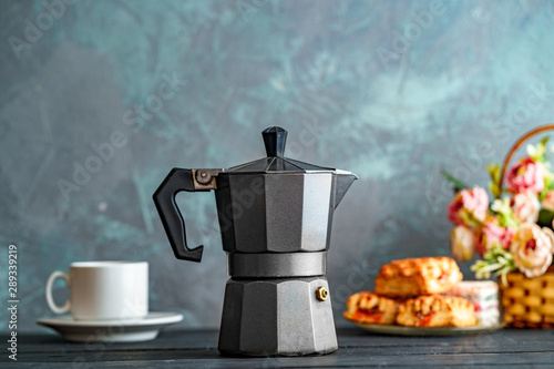 Mocha coffee maker, flowers and sweets on dark background for coffee time