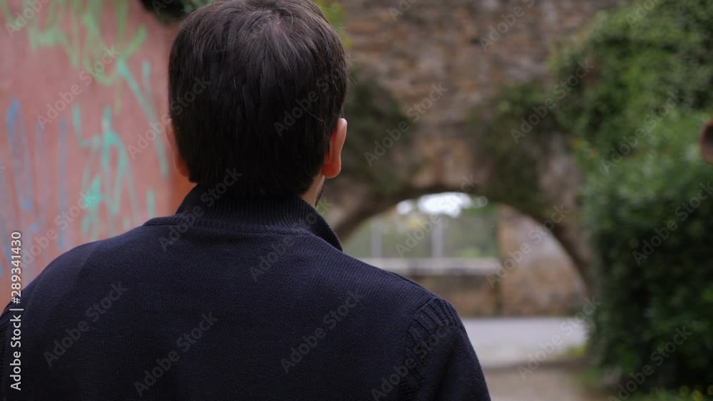young man walking in a street in the town-back view-slow motion young man walking in a street in the town-back view-slow motion