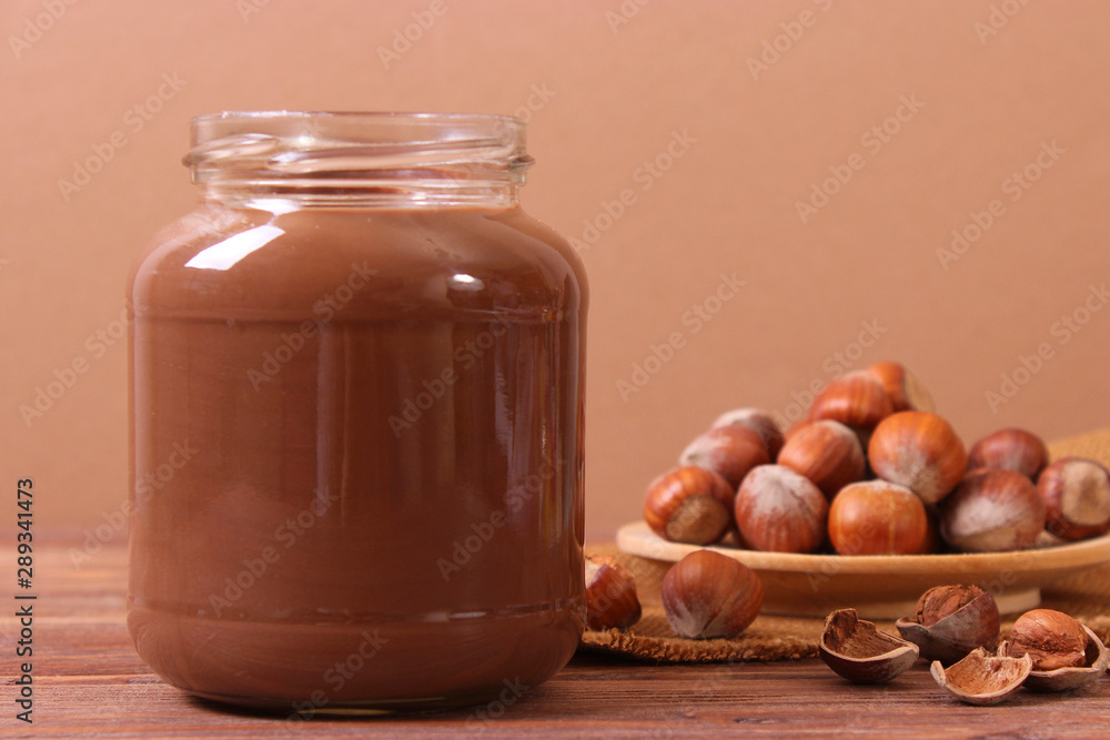 chocolate paste in a glass jar on a colored background. Chocolate butter, chocolate sauce. chocolate paste in a glass jar on a colored background. Chocolate butter, chocolate sauce.