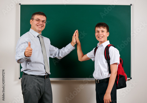 Portrait of a teacher and schoolboy playing at blackboard background - back to school and education concept