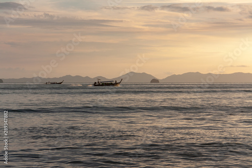 Traditional long boat with tourists sailing by the island in the evening  Thailand.