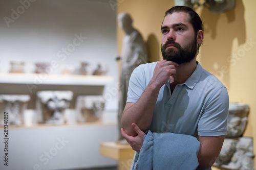 Man looking at stone architectural elements in historical museum hall