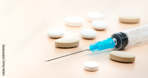 Various pharmaceutical medicine pills, tablets and syringe close-up on a soft beige background. Healthcare and pharmaceuticals. Pills background, copy space.