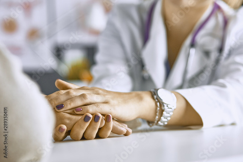 Woman doctor calms patient and holds hand