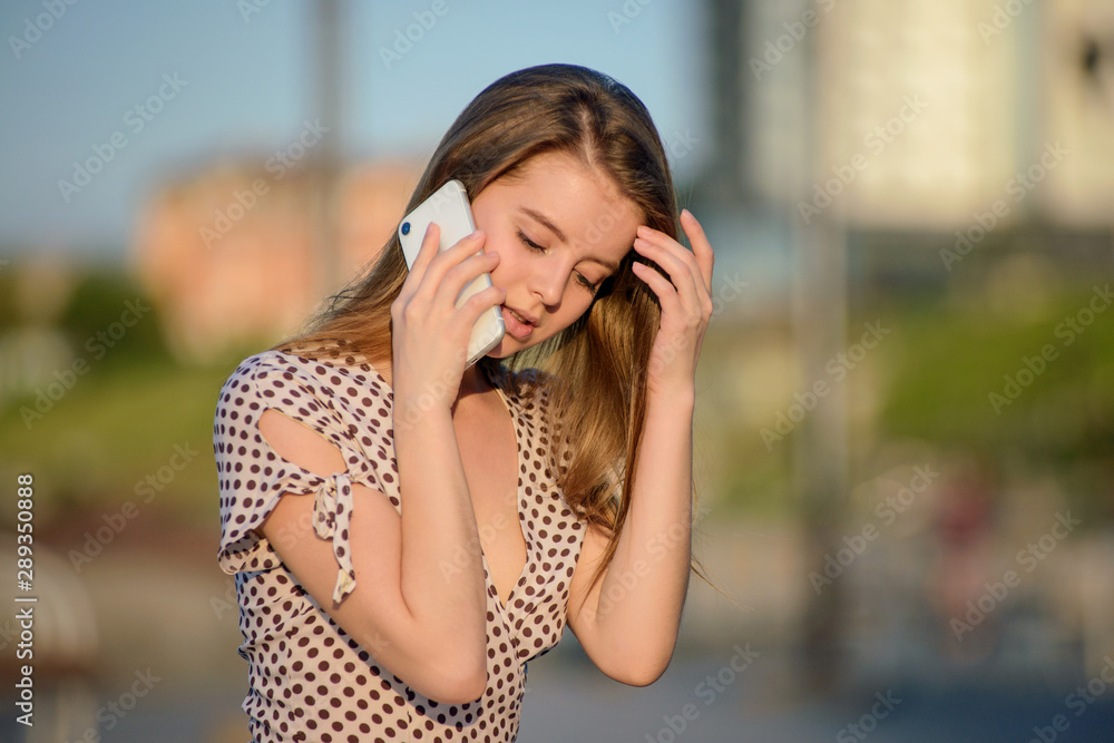 Beautiful girl in a light dress talking on the phone