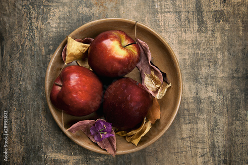 Apples in the bowl, brown color.Autumn leaves decorating.Aged background.View from the top.Top.