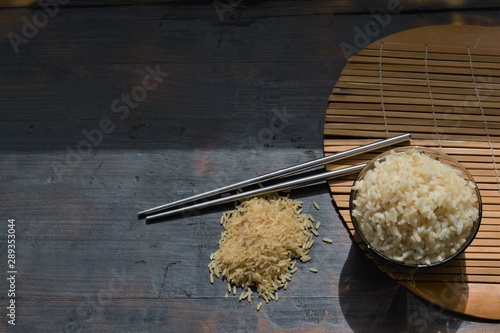 brown rice milled rice imperfectly cleaned unpolished rice in the bowl on a wooden table  black background photo