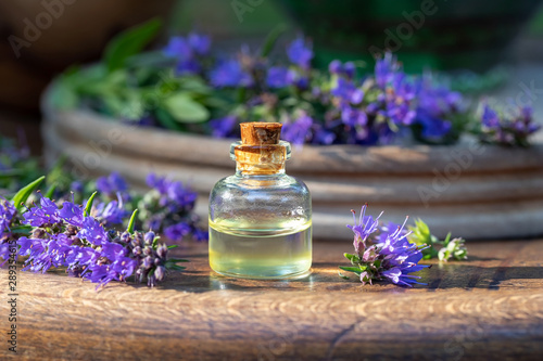 A bottle of essential oil with fresh hyssop flowers