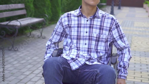 Portrait young asian man disabled in wheelchair rides in park slow mo photo