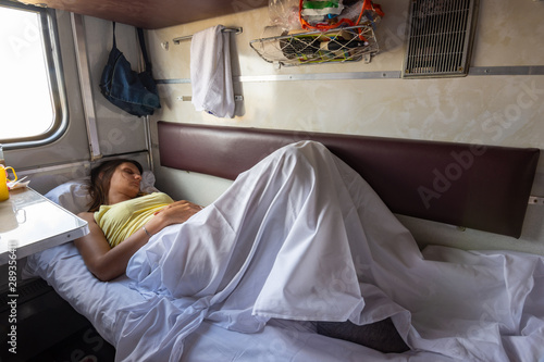 Obraz na plátne A young girl sleeps on a lower bunk in a reserved seat of a train car