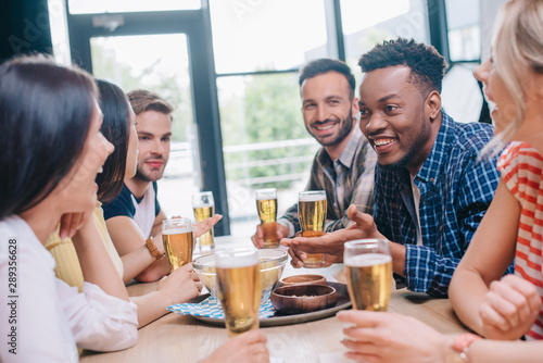 cheerful multicultural friends talking while sitting together in pub © LIGHTFIELD STUDIOS