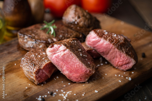 rare grilled tenderloin beef steak on cutting board with vegetables photo