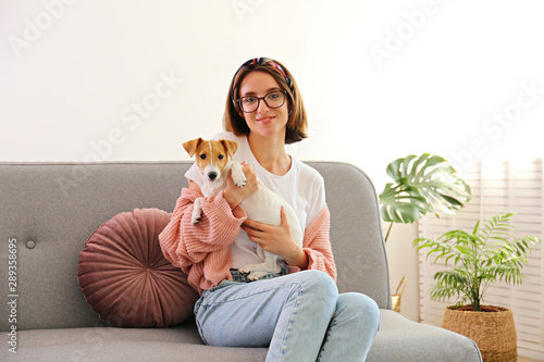 Fototapeta Portrait of young beautiful hipster woman with her adorable four months old jack russell terrier puppy at home in living room full of natural sunlight