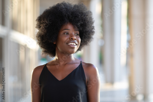Portrait of smiling young black woman with sunlight flare and copy space