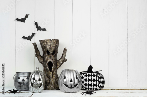 Rustic Halloween display with jack o lantern decor and spooky tree against a white wood background with copy space photo