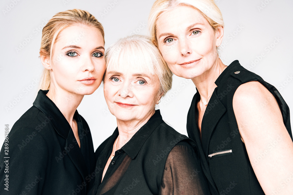 portrait of elegant three-generation blonde women in total black outfits isolated on grey portrait of elegant three-generation blonde women in total black outfits isolated on grey