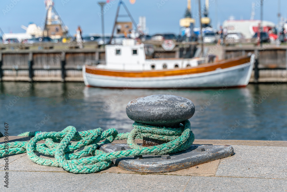 Thick rope Bollard On A Pier. Ship In the background in blur