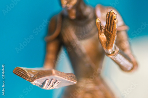 Obraz na plátně Closeup of the hand of a bronze statue holding an open book and another hand up