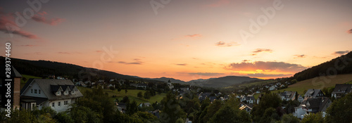 Wide panoramic view over the mountainous spa village of Grafschaft in the winter sports region of Sauerland, Germany, during sunset with a deep orange sky photo