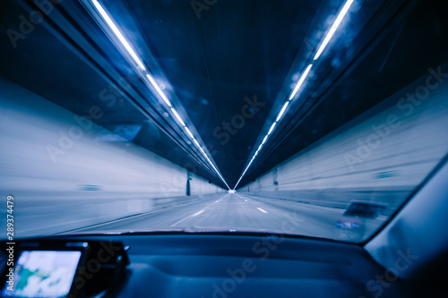 Perspective view fron the car at the long blue tunnel with end at the end