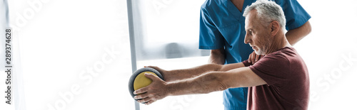 panoramic shot of middle aged man exercising with ball near doctor photo