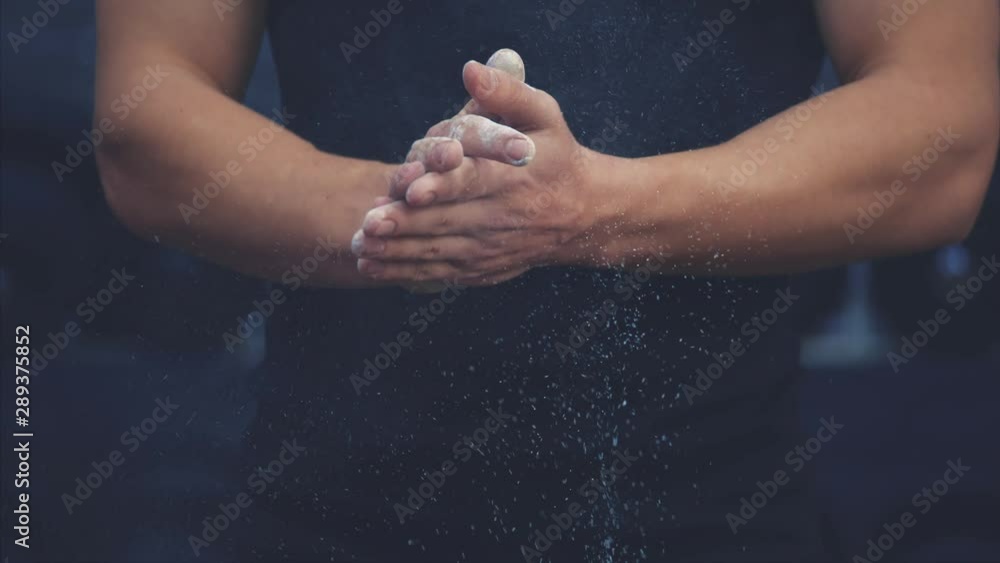 Sporty young guy wearing a black T-shirt. A man with a sporty body puts a hand on his hand and flourishes. During this time he is in the gym. Sporty young guy wearing a black T-shirt. A man with a sporty body puts a hand on his hand and flourishes. During this time he is in the gym.