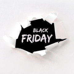Black friday text in paper hole teared in white paper over black background