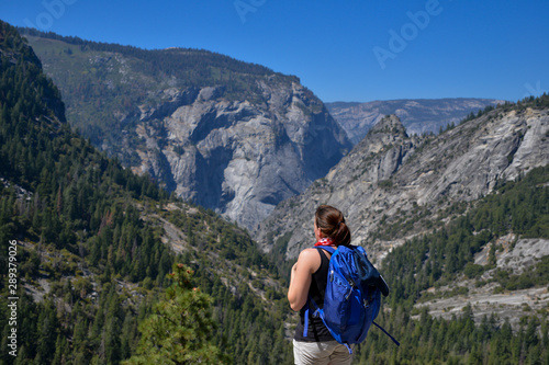 Young woman stands enjoying the view out over Yosemite National Park in the summer.