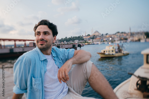 Portrait of a young man against the background of the sea  city  pier and ships.