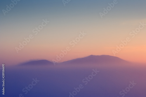 Minimalistic winter landscape. Mountain peaks above the frosty fog. Amazing sunset. Cold winter weather. Majestic Arctic scenery. Mount Dionysius, Chukotka, Far East Russia. Perfect for background.