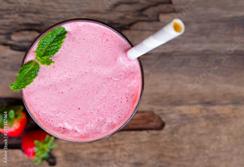 Strawberry smoothies red colorful fruit juice milkshake blend beverage healthy high protein the taste yummy In glass drink episode morning on wood background from the top view.