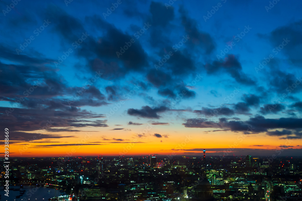 Golden hour - dark blue clouds with an orange light sky background and city light midnight evening time
