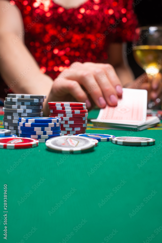 Fototapeta premium A girl in an evening red dress plays in a casino and draws cards. Gambling business casino