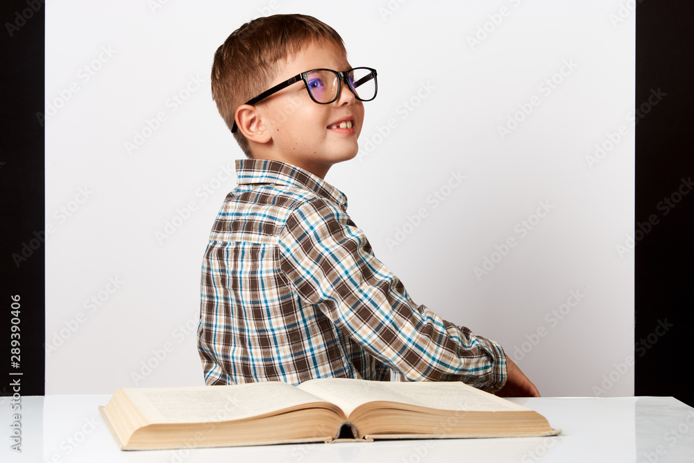 School boy sitting turn back at the table with school book School boy sitting turn back at the table with school book