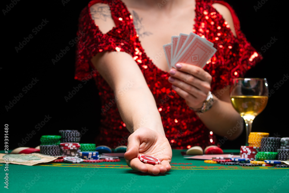 A girl in an evening red dress plays in a casino, holds a chip for a croupier. Gambling business casino A girl in an evening red dress plays in a casino, holds a chip for a croupier. Gambling business casino