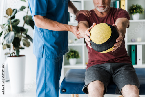 cropped view of mature man training with ball near doctor © LIGHTFIELD STUDIOS