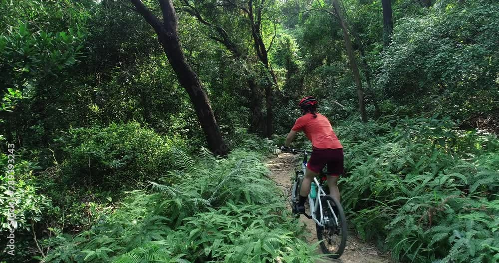 Woman cyclist cross country biking in tropical forest Woman cyclist cross country biking in tropical forest