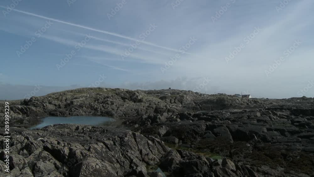 Steady, medium wide shot of rocky terrain surrounding a small creek, homes and interesting clouds in the background. Steady, medium wide shot of rocky terrain surrounding a small creek, homes and interesting clouds in the background.
