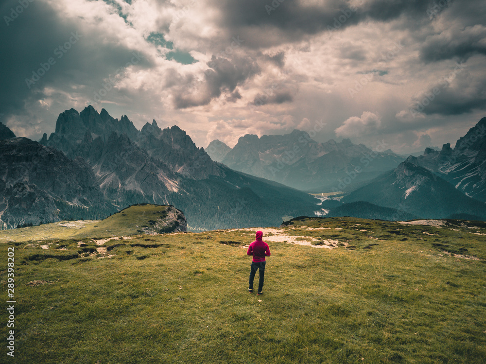 Naklejka premium young man enjoying the view of the mountains landscape in the dolomites mountain range.