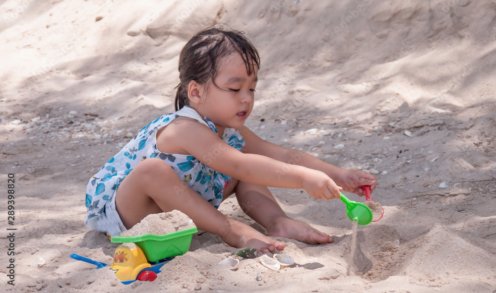 little girl playing with a toy excavator in the sand at the beach of Cha-am, Thailand. little girl playing with a toy excavator in the sand at the beach of Cha-am, Thailand.