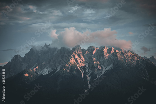 Mountain range in morning sunrise with sun flare in the dolomites italy during summer